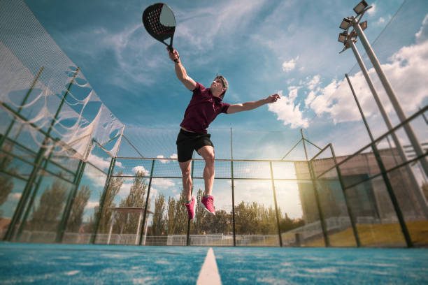 Un jeune joueur de padel qui sautent lors de la réception d'une balle de padel durant un match de padel